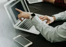 A man focused on a laptop computer, typing intently in a well-lit room